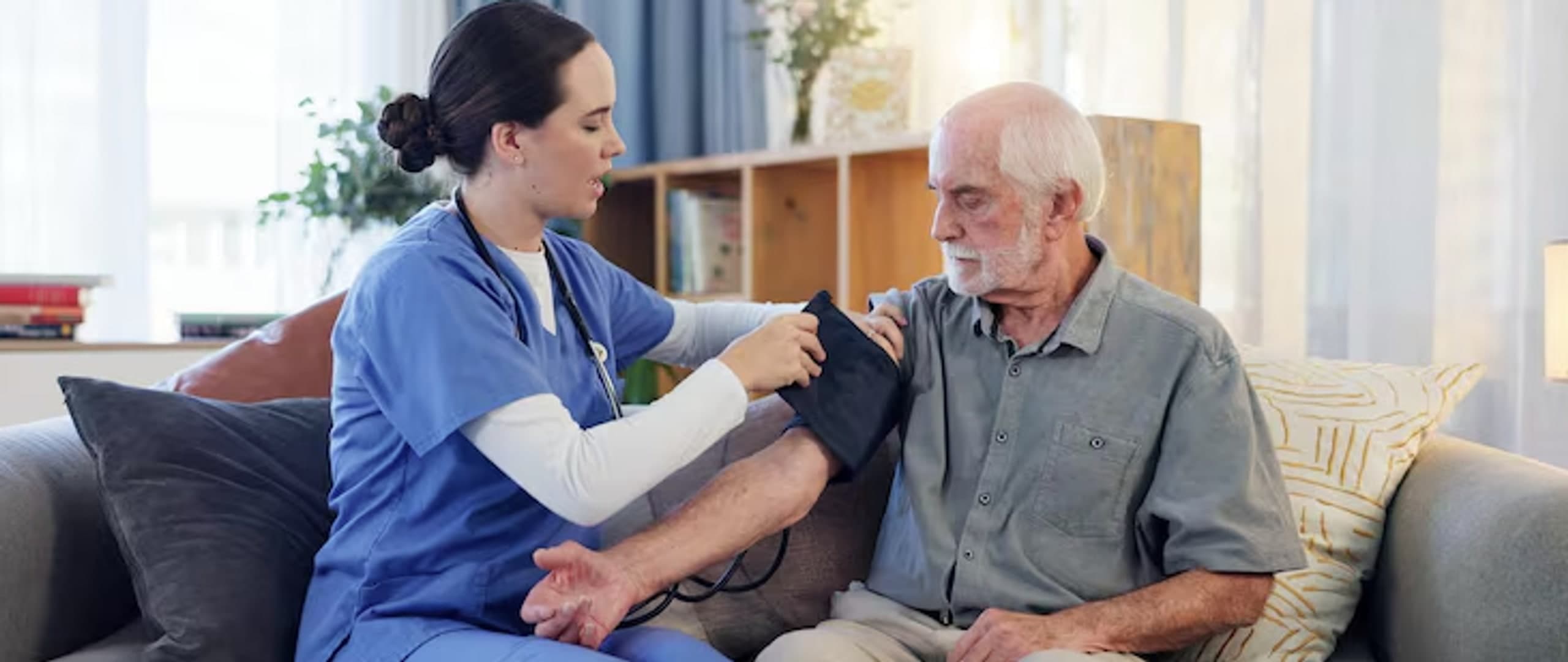 Home health nurse checking an elderly man's blood pressure at home