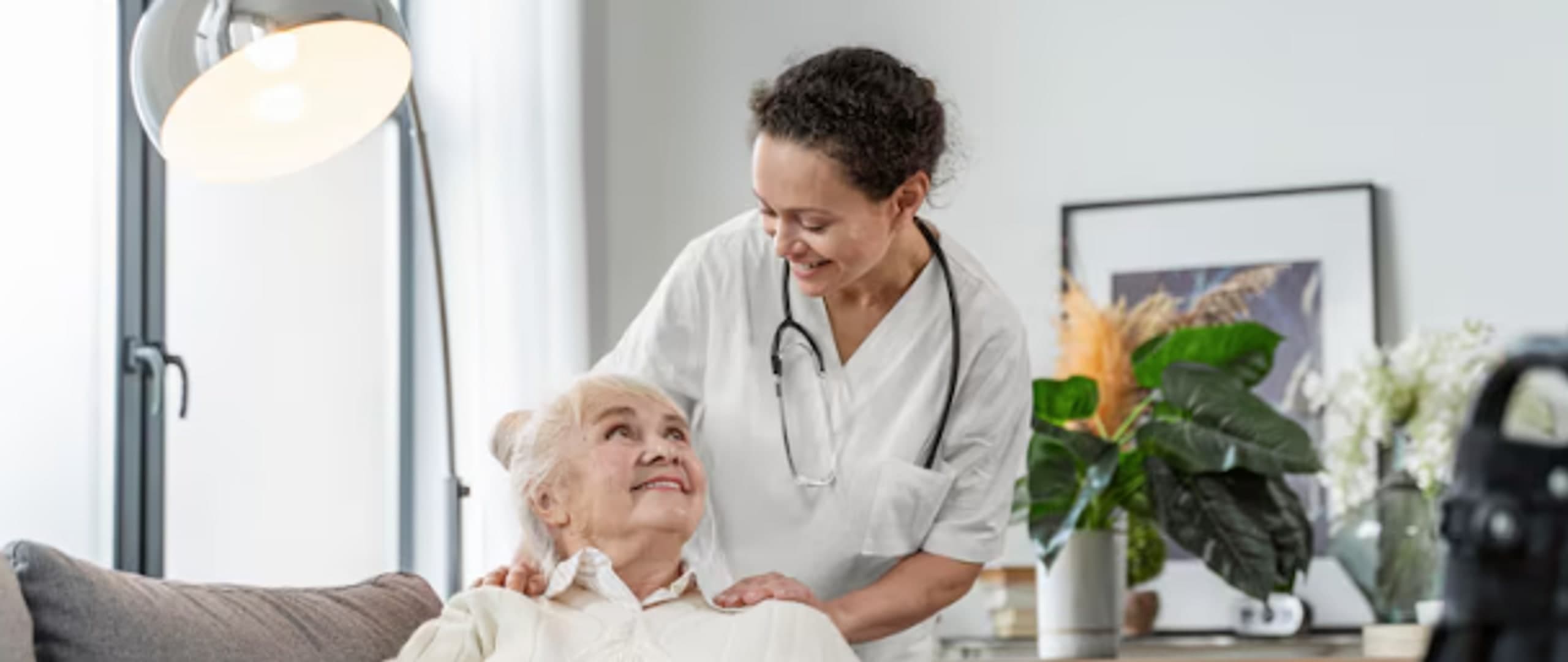 Smiling nurse comforting an elderly woman resting on a couch